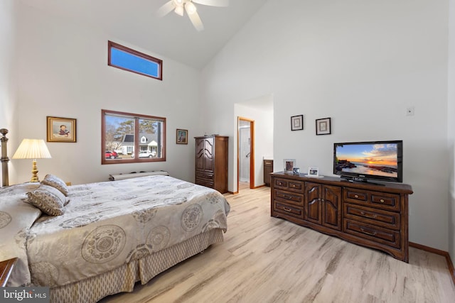 bedroom featuring baseboards, high vaulted ceiling, ceiling fan, ensuite bathroom, and light wood-type flooring