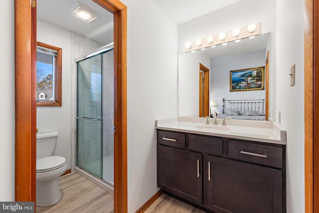 ensuite bathroom featuring a stall shower, toilet, wood finished floors, and ensuite bathroom