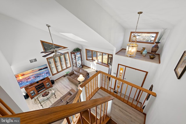 stairs with a skylight, wood finished floors, visible vents, and high vaulted ceiling