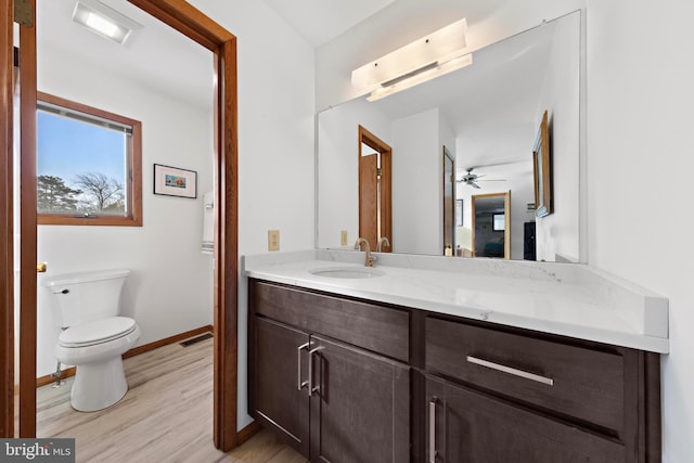 bathroom featuring visible vents, toilet, wood finished floors, baseboards, and vanity