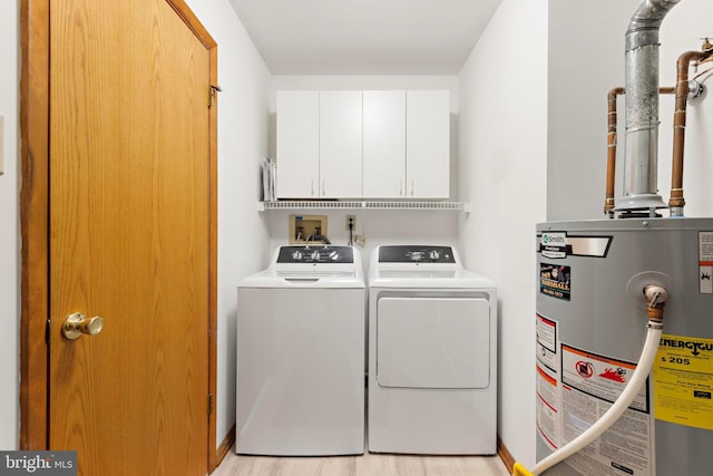 clothes washing area with cabinet space, gas water heater, light wood finished floors, and washing machine and clothes dryer