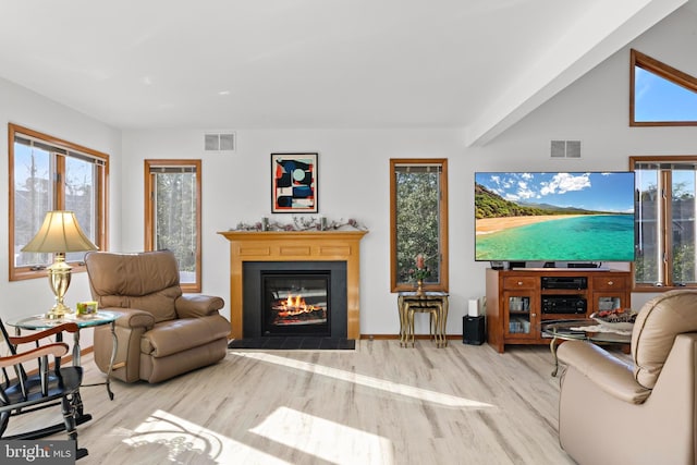 living area with visible vents, baseboards, a glass covered fireplace, and wood finished floors