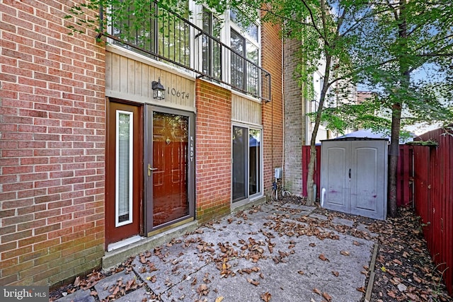 view of exterior entry with fence and brick siding