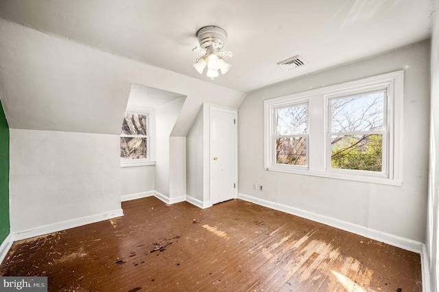 bonus room with hardwood / wood-style floors, lofted ceiling, baseboards, and visible vents