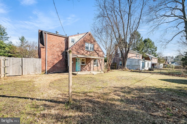 back of house with a yard, brick siding, and a fenced backyard