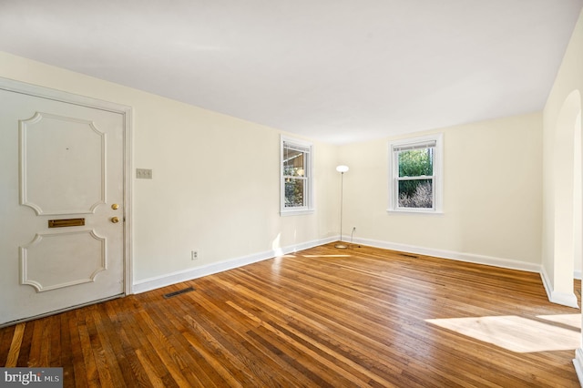 spare room featuring visible vents, baseboards, and wood-type flooring