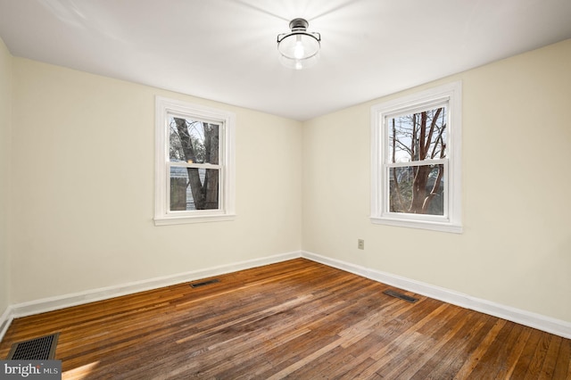 spare room featuring visible vents, wood-type flooring, and baseboards