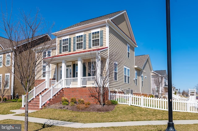 view of front facade with covered porch, a front lawn, and fence