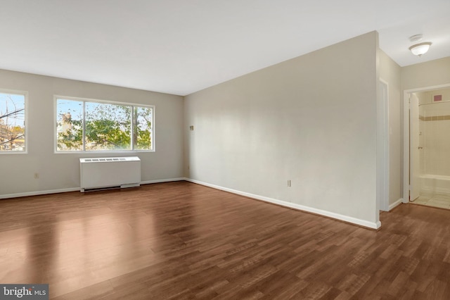 spare room featuring radiator heating unit, baseboards, and wood finished floors