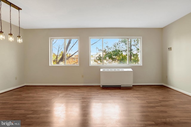 empty room featuring radiator heating unit, baseboards, and wood finished floors