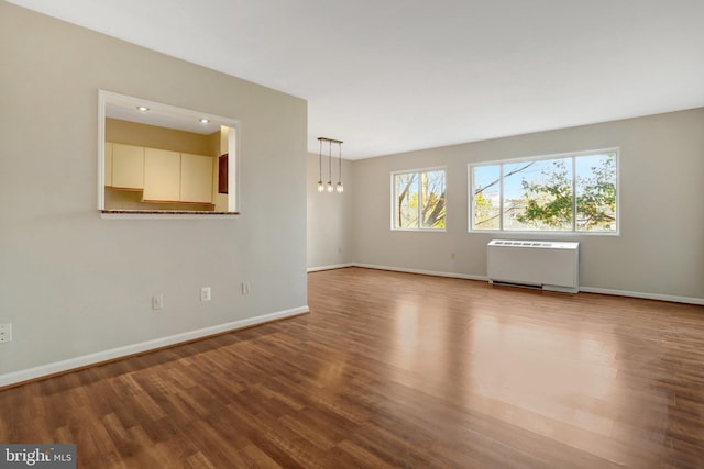 unfurnished room featuring radiator heating unit, wood finished floors, and baseboards