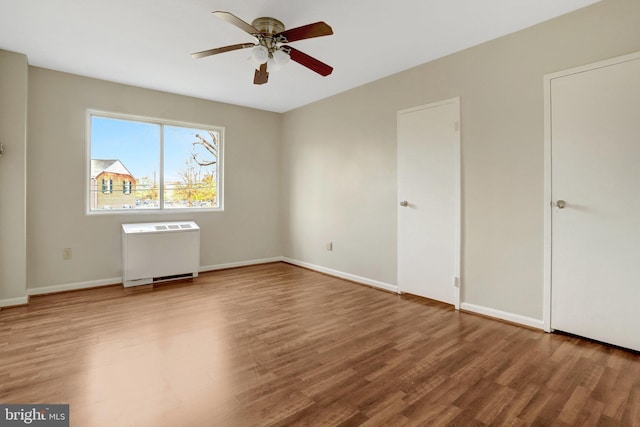 unfurnished bedroom with ceiling fan, baseboards, radiator, and wood finished floors