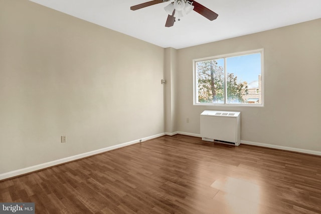 empty room featuring radiator heating unit, wood finished floors, baseboards, and ceiling fan