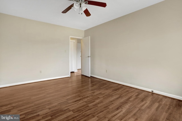 empty room with dark wood-type flooring, a ceiling fan, and baseboards