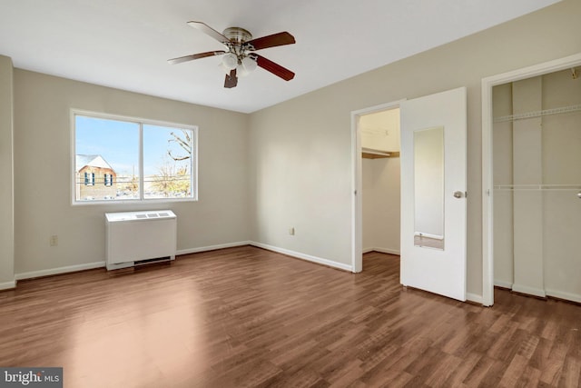 unfurnished bedroom featuring a ceiling fan, radiator, wood finished floors, and baseboards