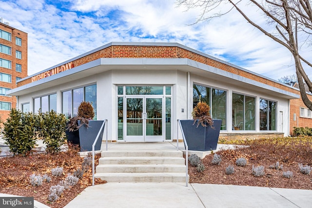 entrance to property featuring stucco siding and french doors