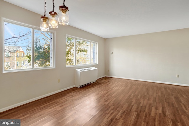 spare room with radiator heating unit, wood finished floors, and baseboards