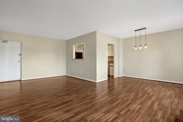 unfurnished living room with dark wood-type flooring and baseboards