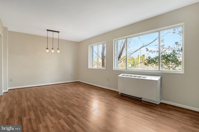 unfurnished room with baseboards, radiator, and wood finished floors