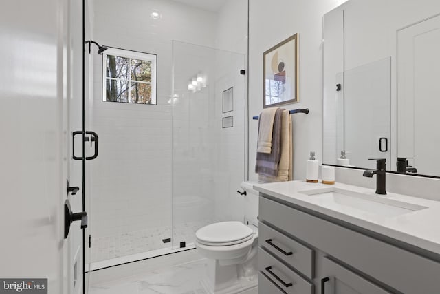 bathroom featuring vanity, toilet, marble finish floor, and a stall shower