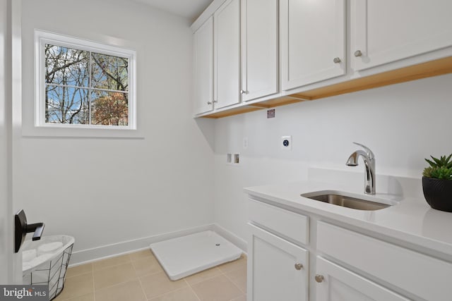 washroom featuring baseboards, hookup for a washing machine, cabinet space, hookup for an electric dryer, and a sink