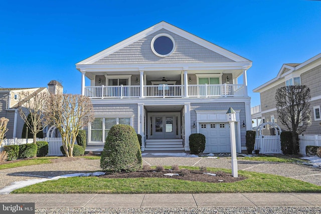 view of front of property featuring a garage, a balcony, driveway, and fence