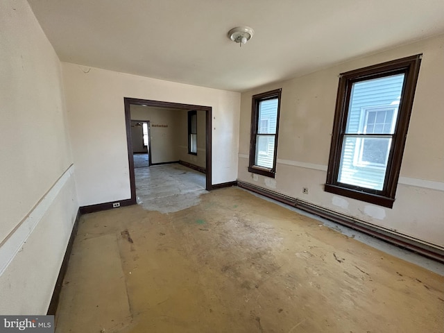 empty room featuring a healthy amount of sunlight, baseboards, and concrete flooring