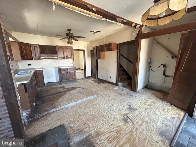 kitchen with a ceiling fan, a sink, backsplash, dark brown cabinetry, and light countertops