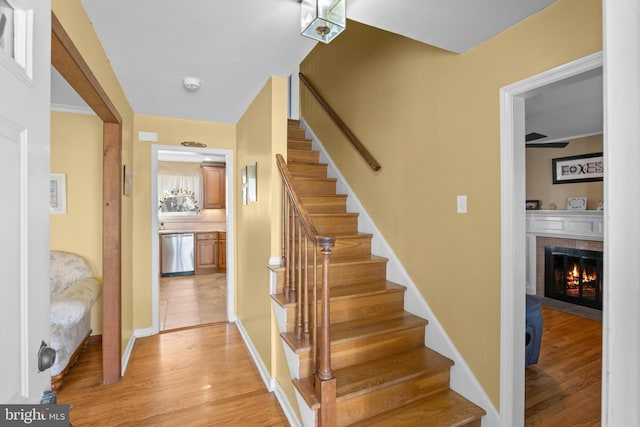 stairs featuring a fireplace with flush hearth, wood finished floors, and baseboards