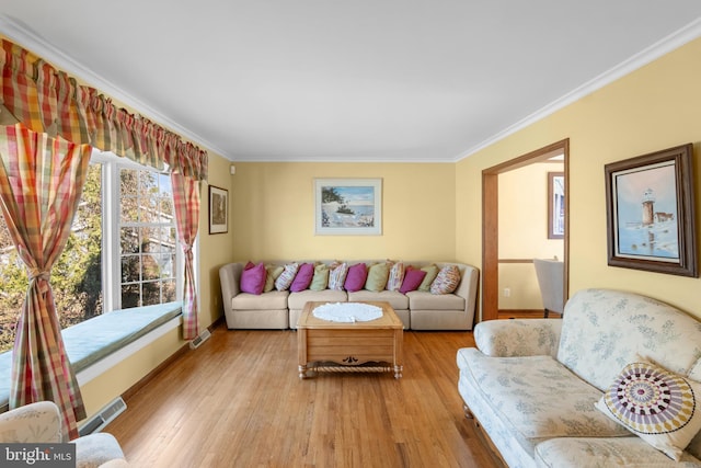 living room with crown molding, light wood-style floors, and visible vents