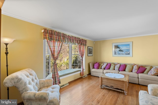 living room with visible vents, crown molding, and wood finished floors