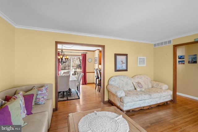 living room featuring visible vents, crown molding, baseboards, an inviting chandelier, and wood finished floors