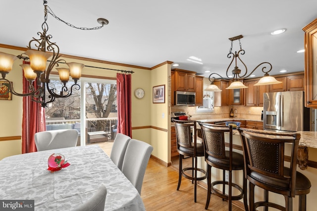 dining space with a notable chandelier, ornamental molding, recessed lighting, light wood finished floors, and baseboards