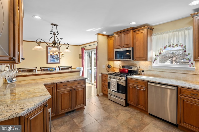 kitchen featuring decorative light fixtures, tasteful backsplash, stainless steel appliances, brown cabinetry, and light stone countertops