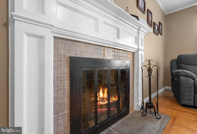 details with wood finished floors, crown molding, a fireplace, and baseboards