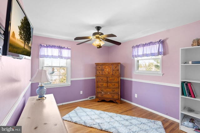 bedroom with a ceiling fan, visible vents, wood finished floors, and baseboards