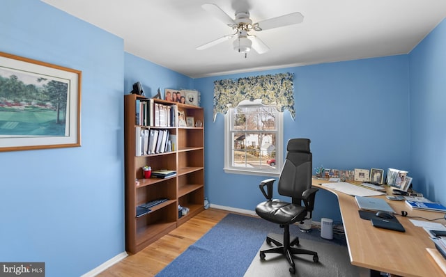 office featuring baseboards, light wood-style floors, and a ceiling fan