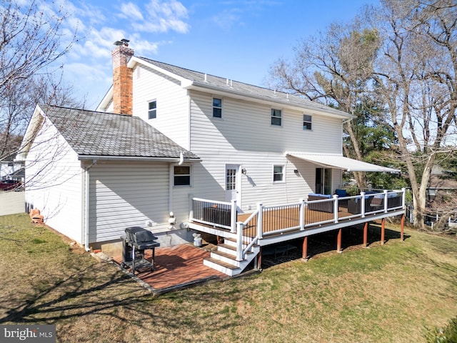 rear view of house featuring a deck, a yard, and a chimney