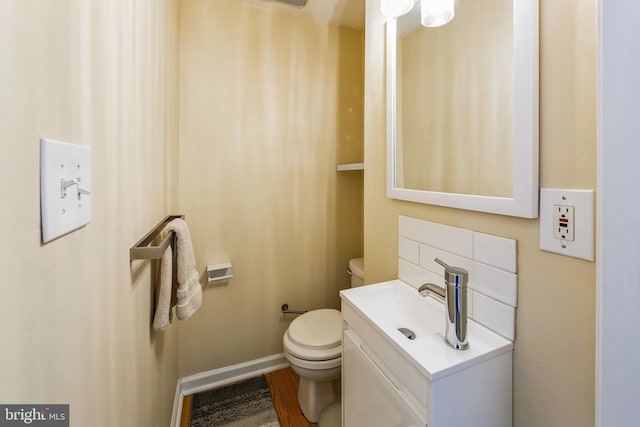 bathroom featuring toilet, vanity, baseboards, and wood finished floors