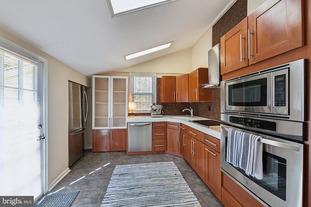 kitchen with stainless steel appliances, a healthy amount of sunlight, light countertops, and wall chimney range hood