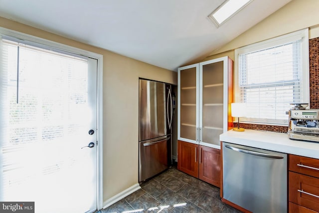 kitchen featuring glass insert cabinets, appliances with stainless steel finishes, light countertops, and vaulted ceiling