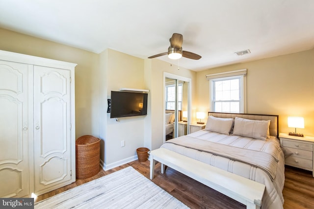 bedroom with ceiling fan, wood finished floors, visible vents, and baseboards