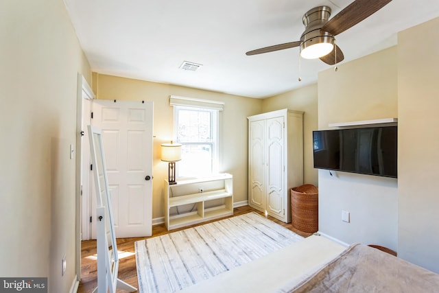 bedroom featuring ceiling fan, visible vents, baseboards, and wood finished floors