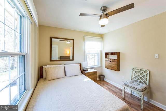 bedroom featuring baseboards, wood finished floors, and a ceiling fan