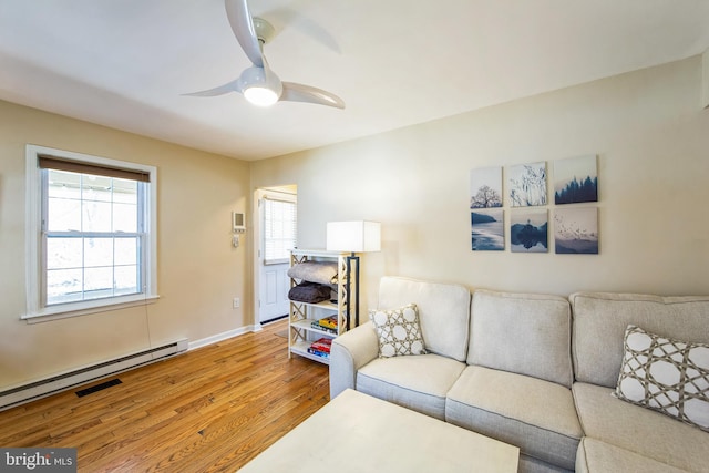 living area with wood finished floors, baseboards, baseboard heating, and ceiling fan