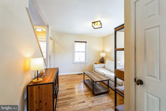 sitting room featuring visible vents, baseboards, light wood-style floors, and a barn door