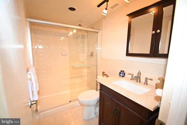 full bath featuring a wainscoted wall, toilet, a stall shower, tile walls, and vanity