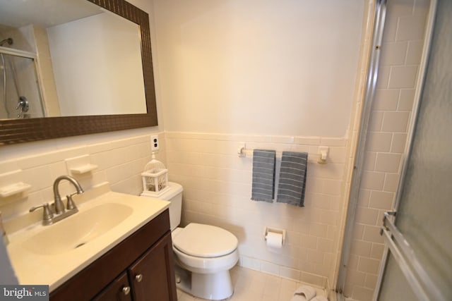 bathroom featuring a shower with shower door, toilet, tile walls, wainscoting, and vanity