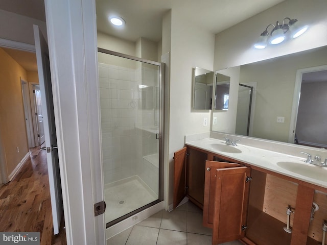 bathroom with a sink, double vanity, a shower stall, and tile patterned flooring