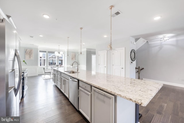 kitchen featuring a sink, dark wood-style floors, appliances with stainless steel finishes, and a large island with sink